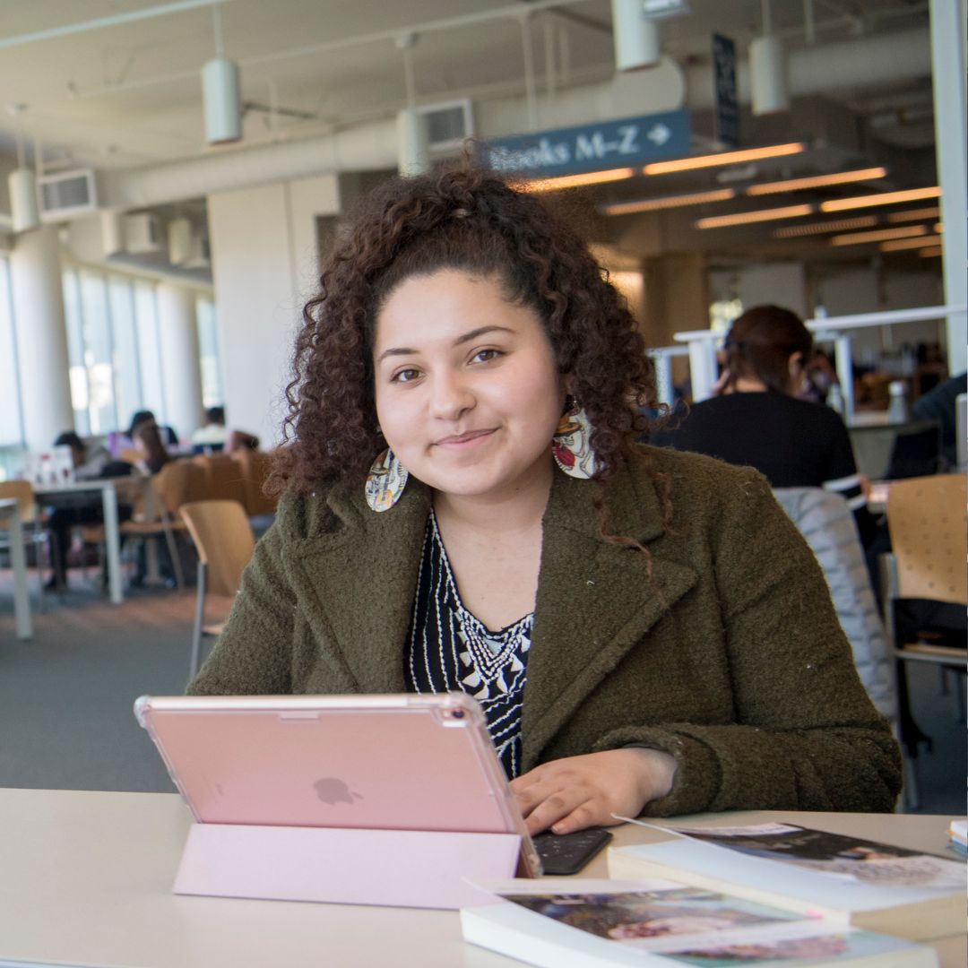 Ethnic Studies student studying in the library on a pink iPad
