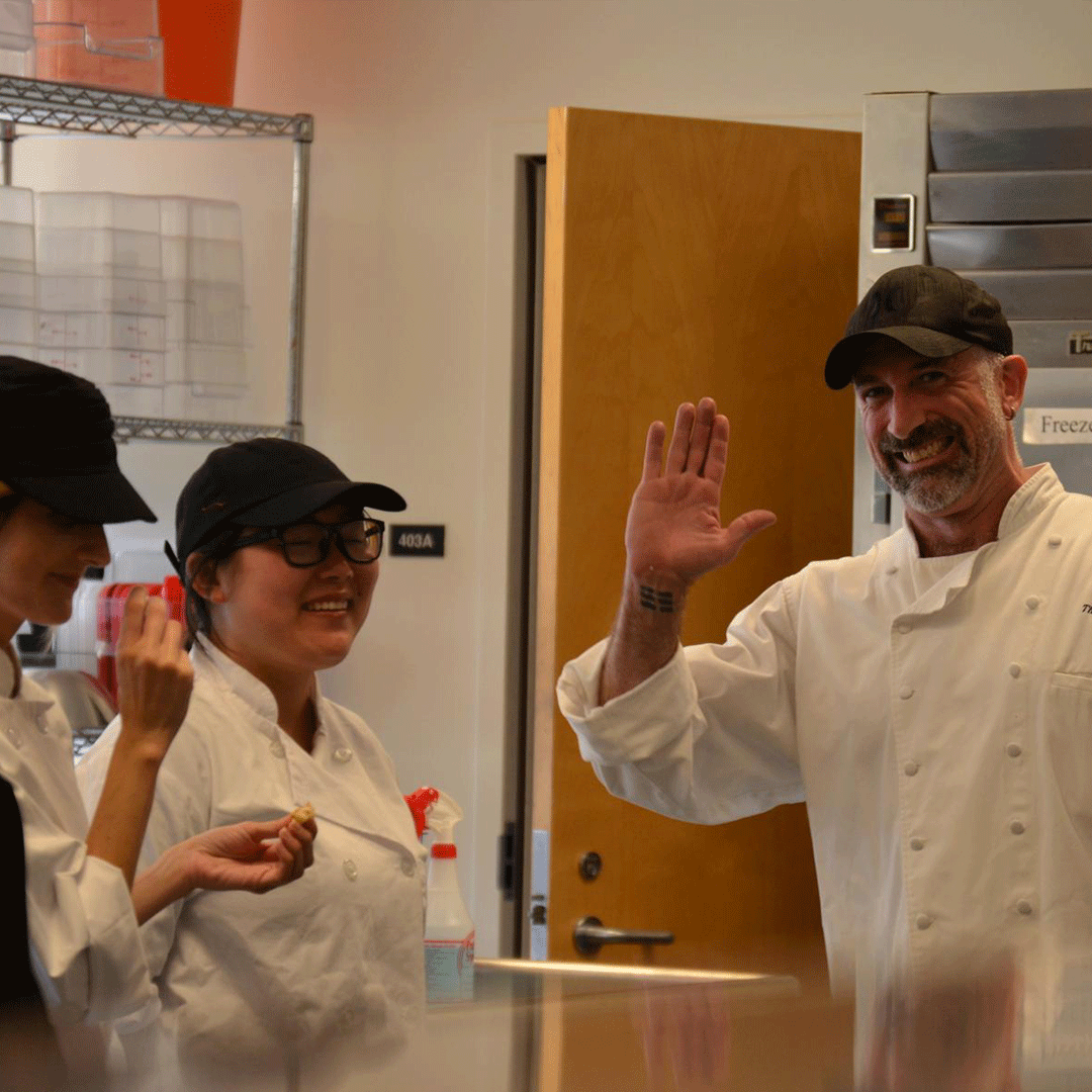 Chef waves and cooks in the kitchen smile