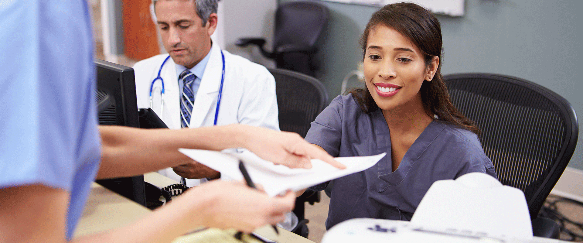 Nurse hands medical administrative assistant some paperwork