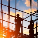 Silhouette of workers and a construction site as the sun sets