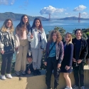 International students with water and the Golden Gate Bridge behind them and cute clouds over it