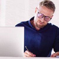 Professional man studying online and taking notes