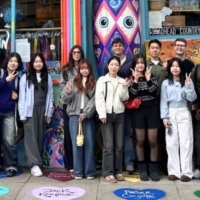 International students on a colorful sidewalk in front of a building with colorful murals