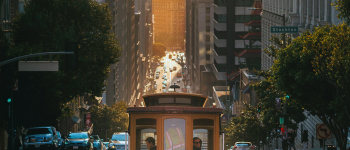 San Francisco cable car on a hill with the Bay Bridge in the background